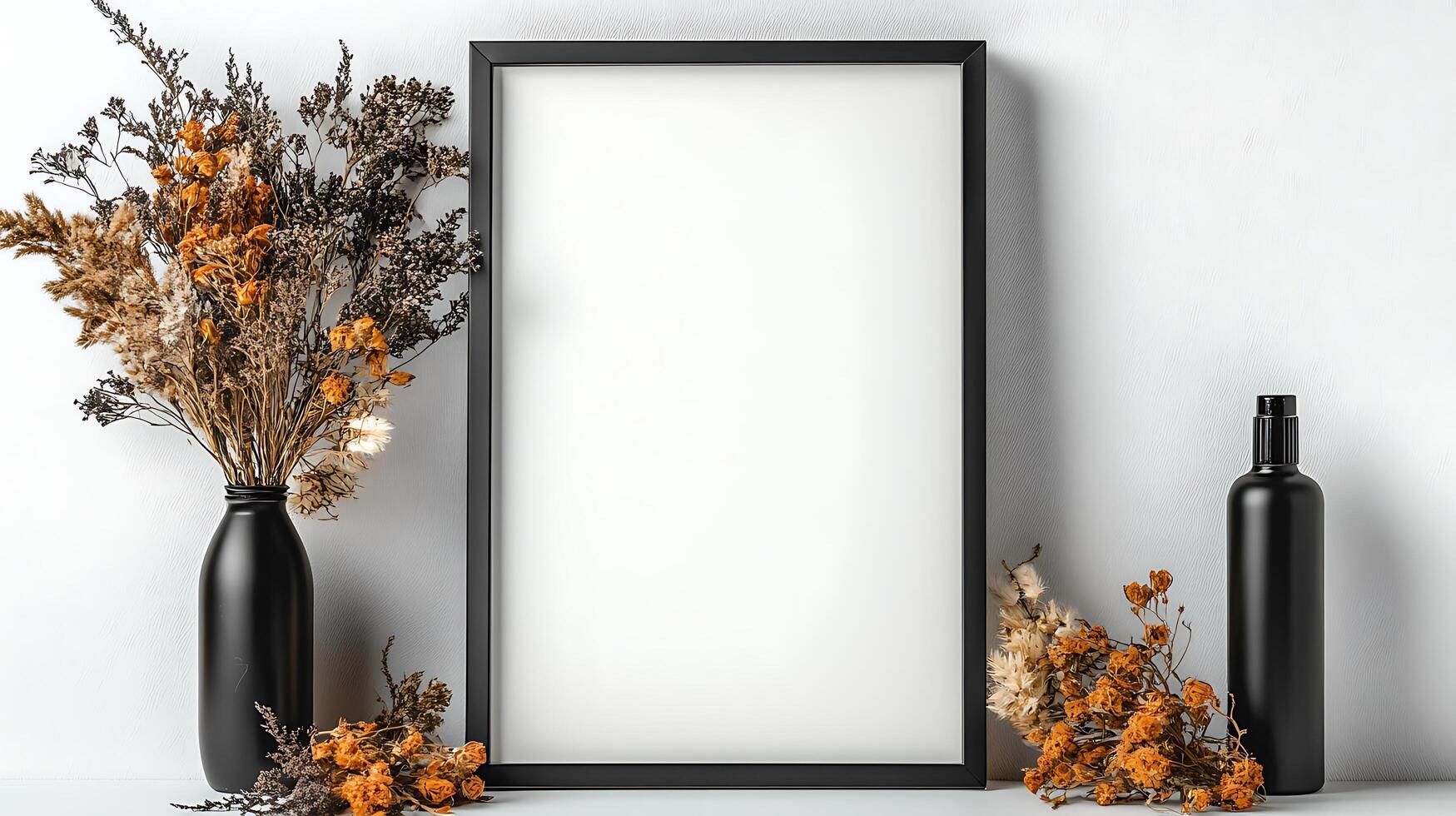 A blank frame with dried flowers and a bottle on a table photo