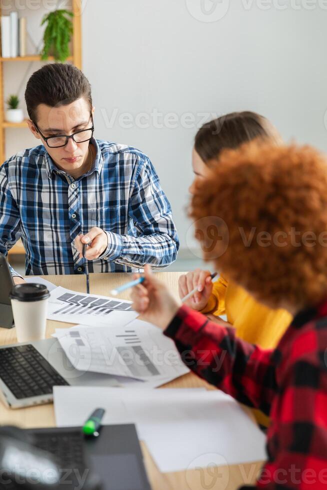 Teamwork brainstorm. Diverse colleagues working together discuss financial statistics. Group of happy young modern people sitting in creative office discussing business. Young professional team photo