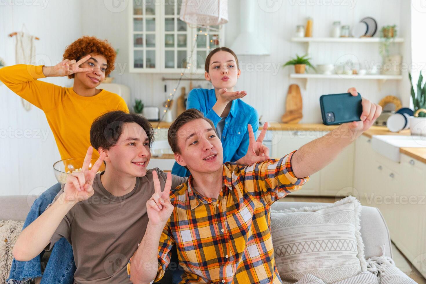 Cheers Funky mood. Happy group of friends make selfie. Man taking photo of friends at party. Group of multiracial young people taking photo on phone. Young people enjoy their company smile have fun