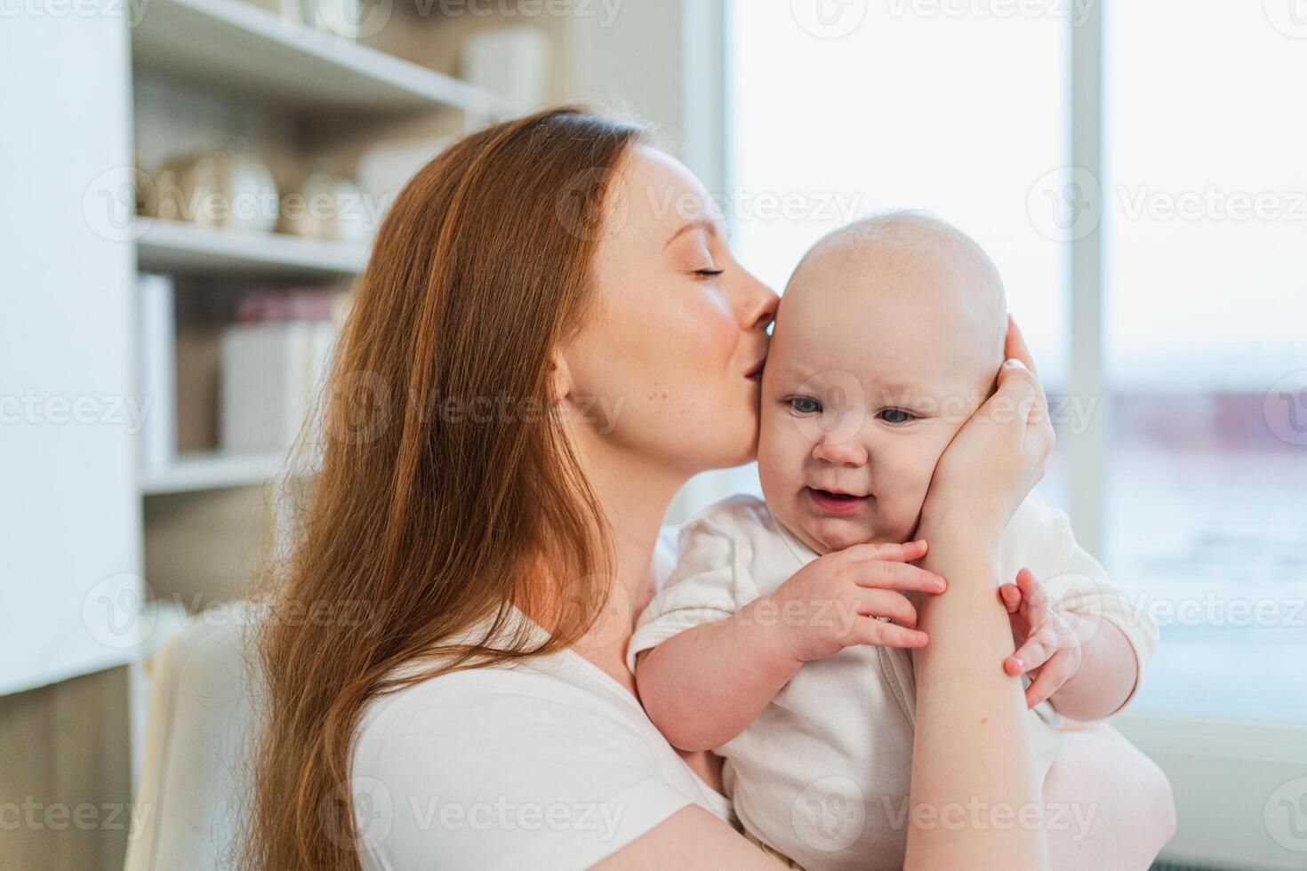 Happy family at home. Mother holding little toddler child daughter. Mom and baby girl relax playing having fun together at home. Mother hugs baby with love care. Mom of breast feeding baby photo