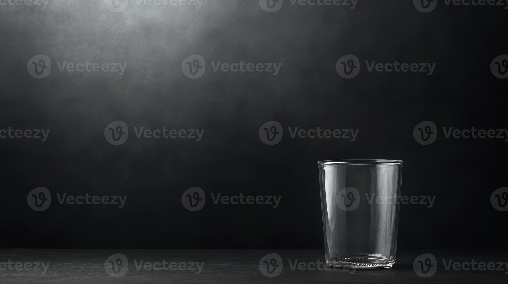 Empty glass resting on a dark surface illuminated by soft light photo