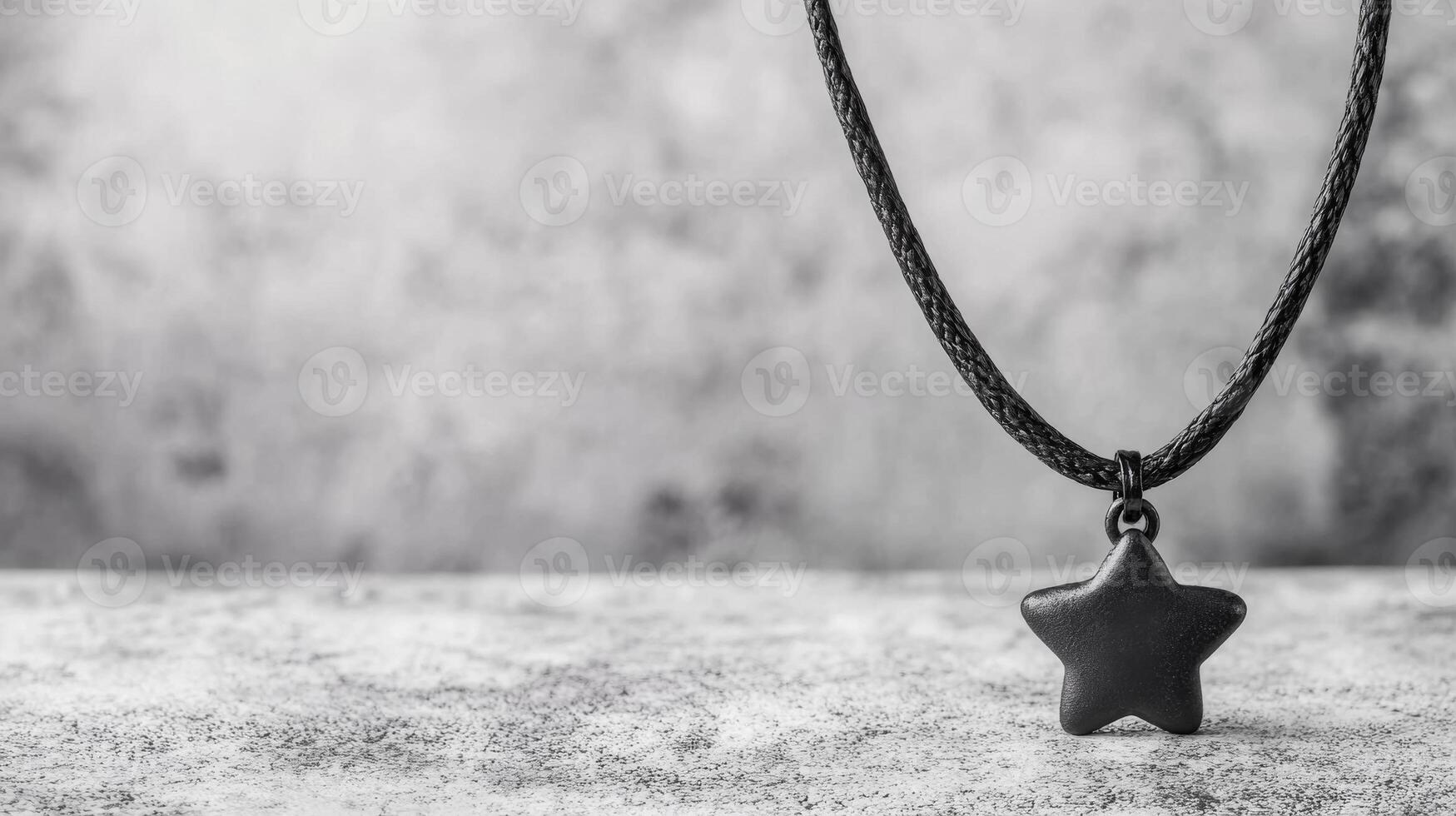 Star pendant hanging from a black cord on a textured surface photo