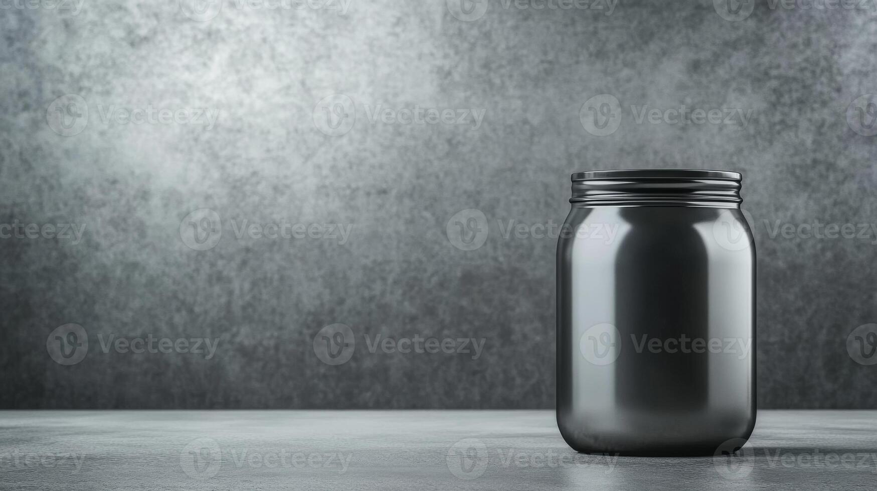 Glass jar with black lid set against a textured gray background photo