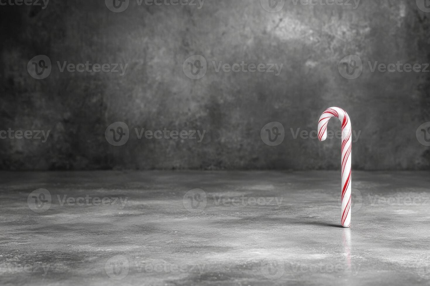 Candy cane standing alone on a textured gray surface during winter photo