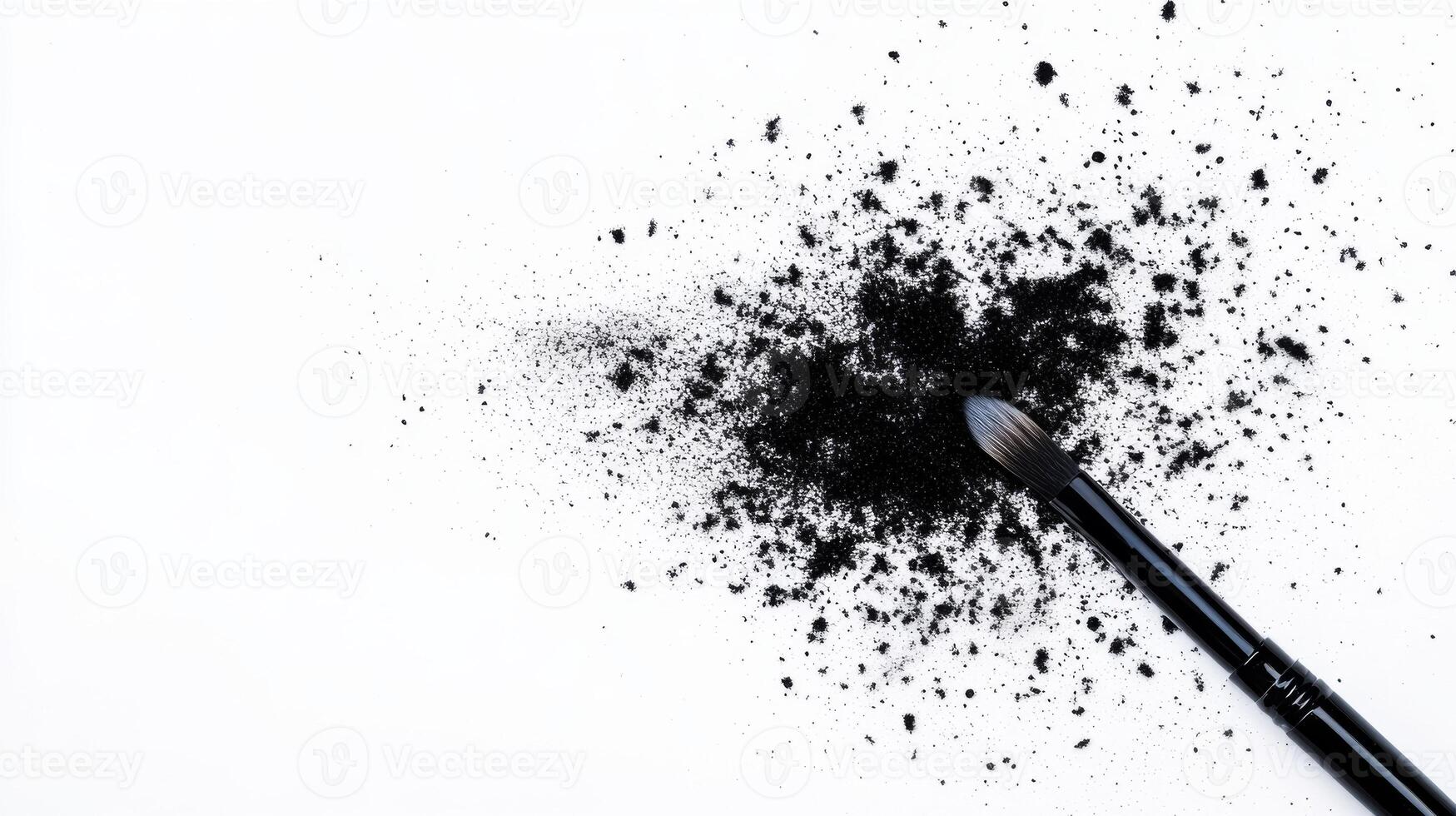 Makeup brush resting beside black powder on white surface photo