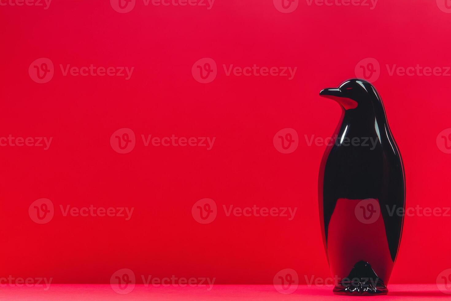 Black penguin figurine on bright red background creating contrast photo
