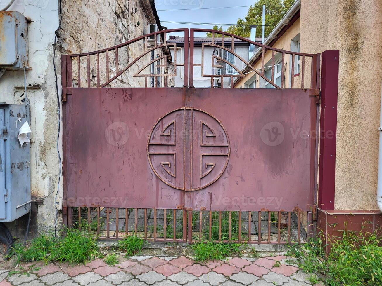 There are red iron gates with forged elements on the street. photo