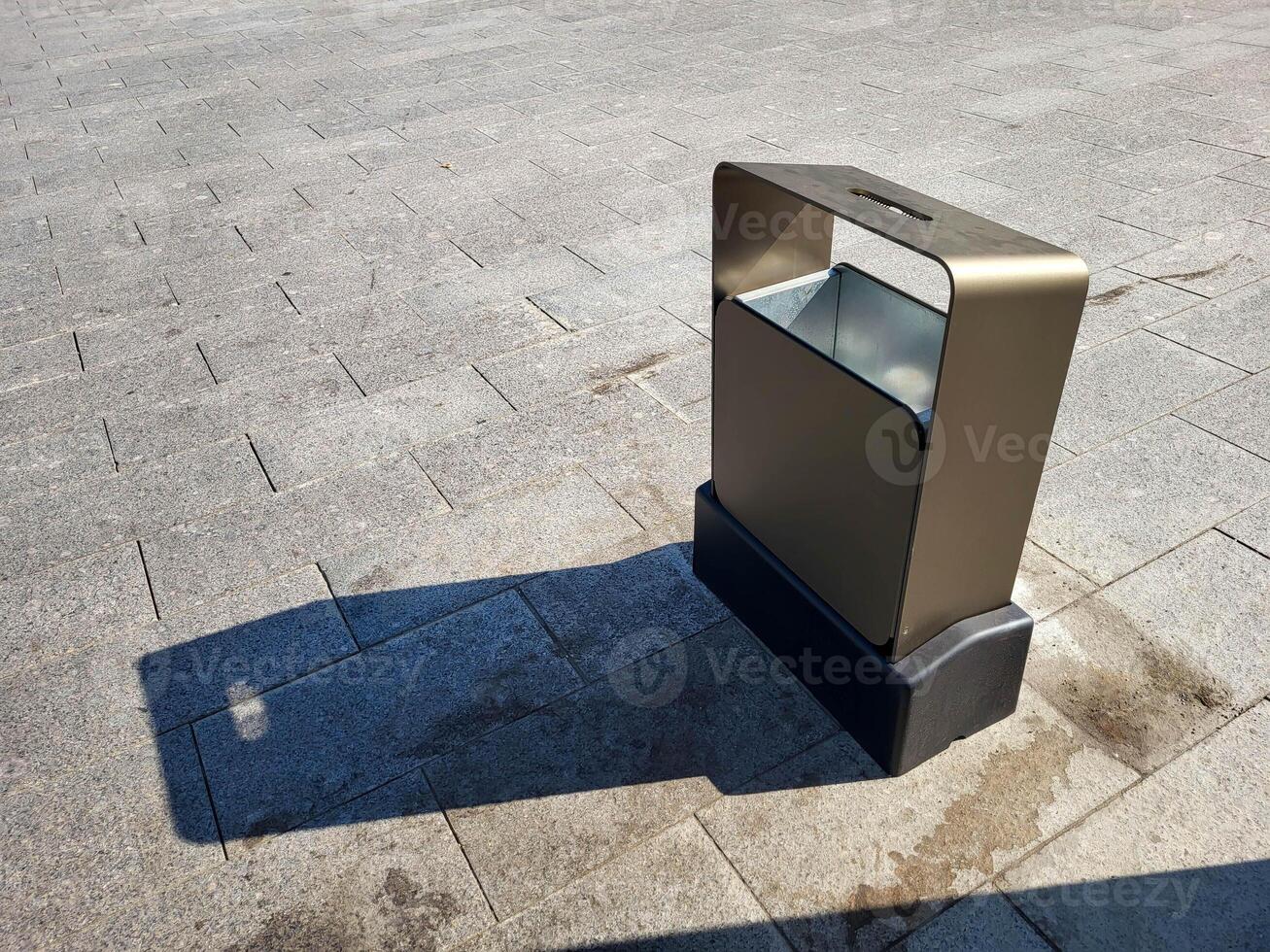 Shiny rectangular metal urn on a city street on a clear sunny day. photo