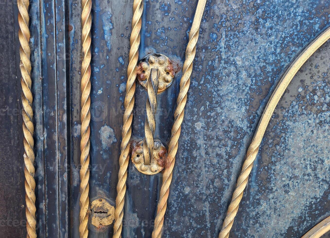 Close-up of a gilded iron gate handle with a twisted pattern. photo