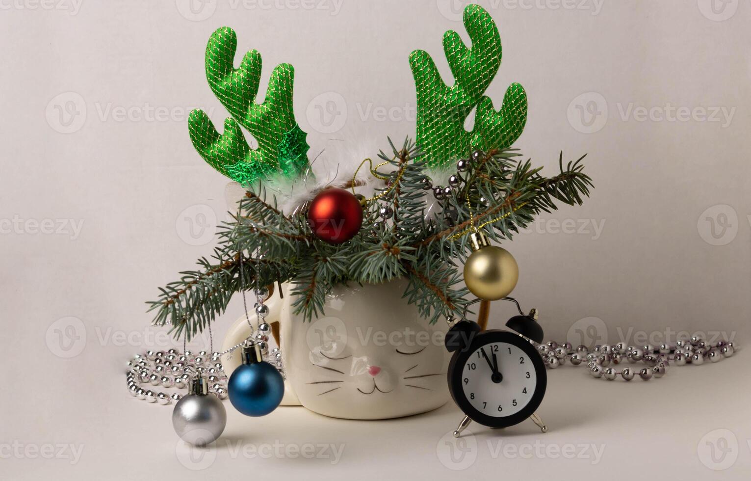 An alarm clock, a hoop with deer antlers and branches of a Christmas tree decorated with toys photo