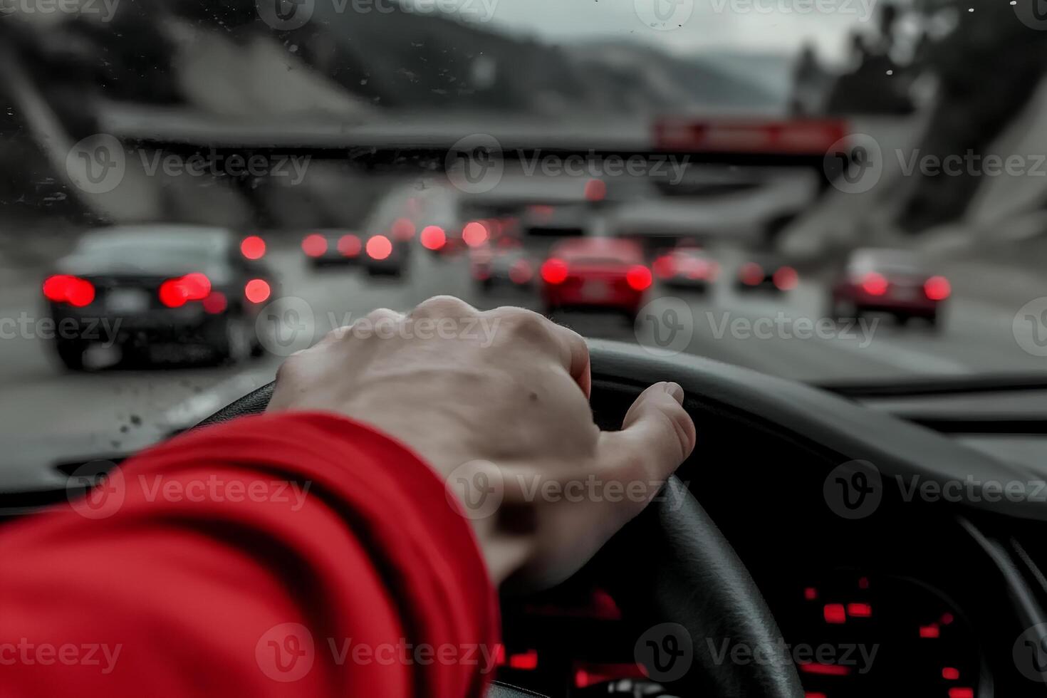 Close-up shot of a woman's hand on the steering wheel while driving through rainy weather, with water droplets on the window photo