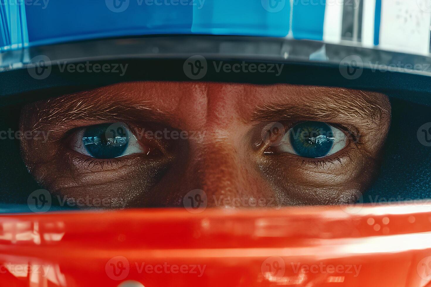 A close-up portrait of a man with striking blue eyes, seated in a race car, fully focused and ready for action on the racetrack photo