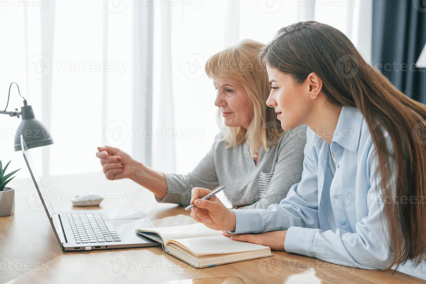 Sitting by table with laptop. Mother and daughter is together at home. photo