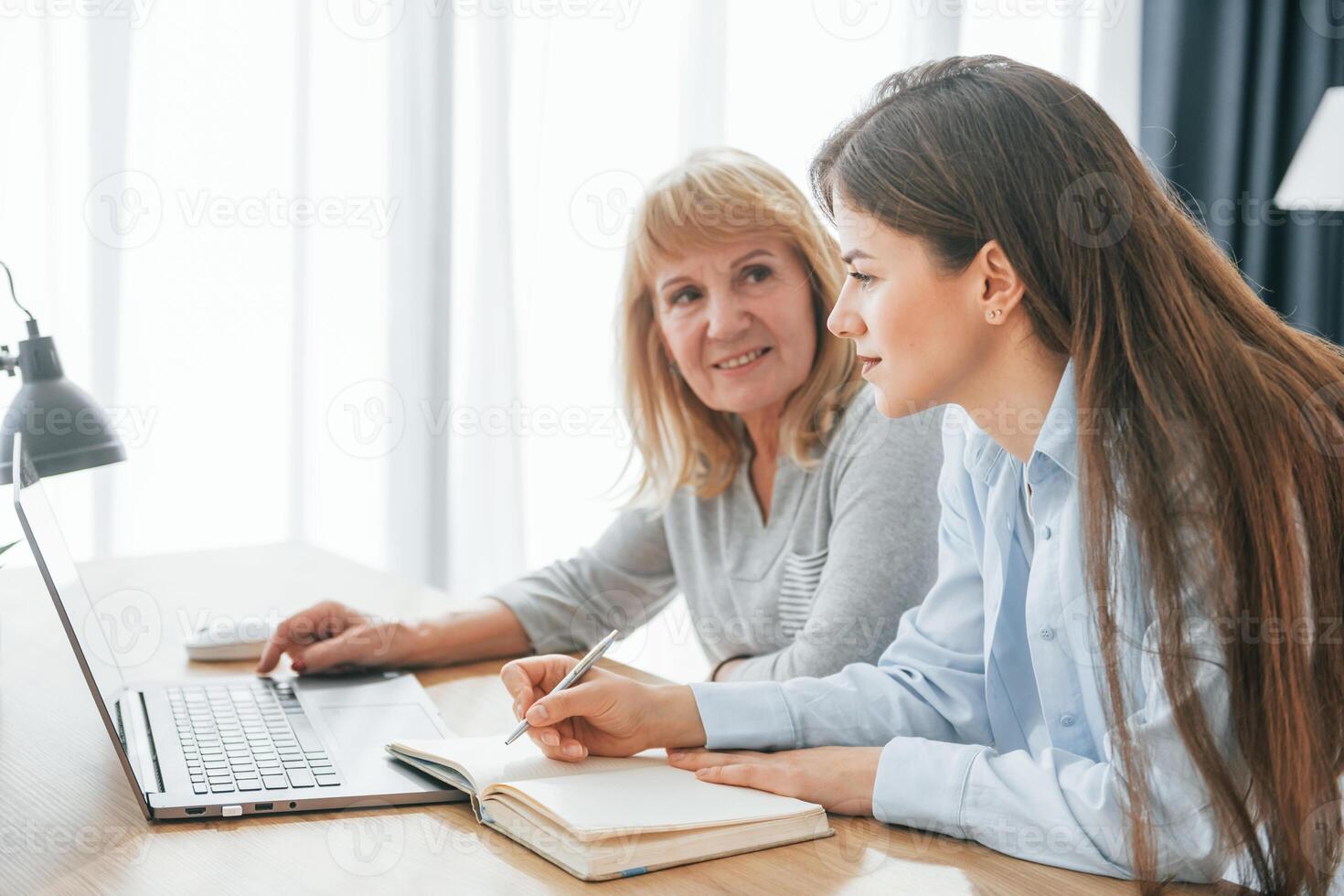 Two women sitting at a table with a laptop photo