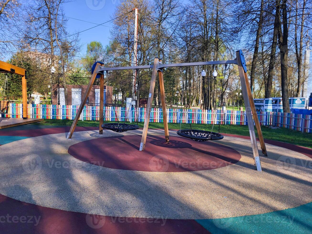 Children's wooden empty swing with a round rope seat in a children's park photo