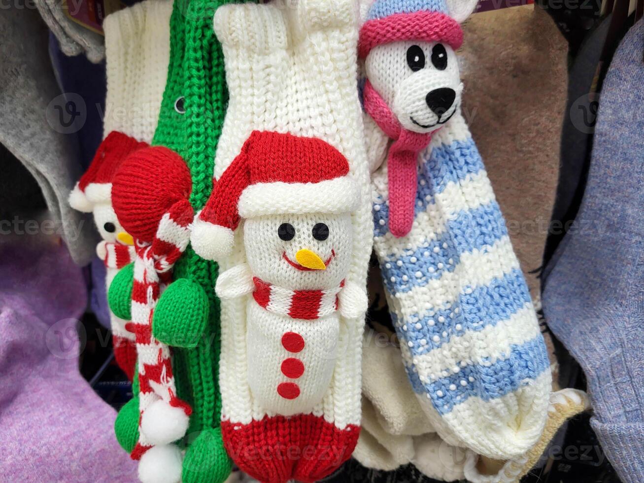 There are knitted white mittens with a snowman hanging in the store. The concept of Christmas and New Year photo