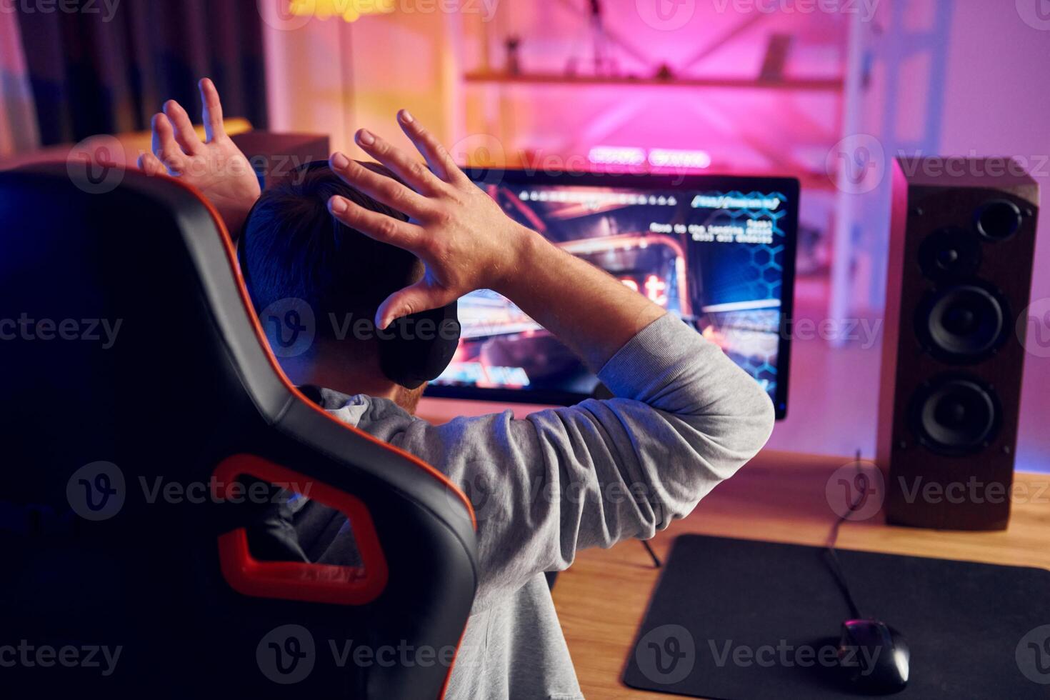 A man sitting in front of a computer with his hands up photo