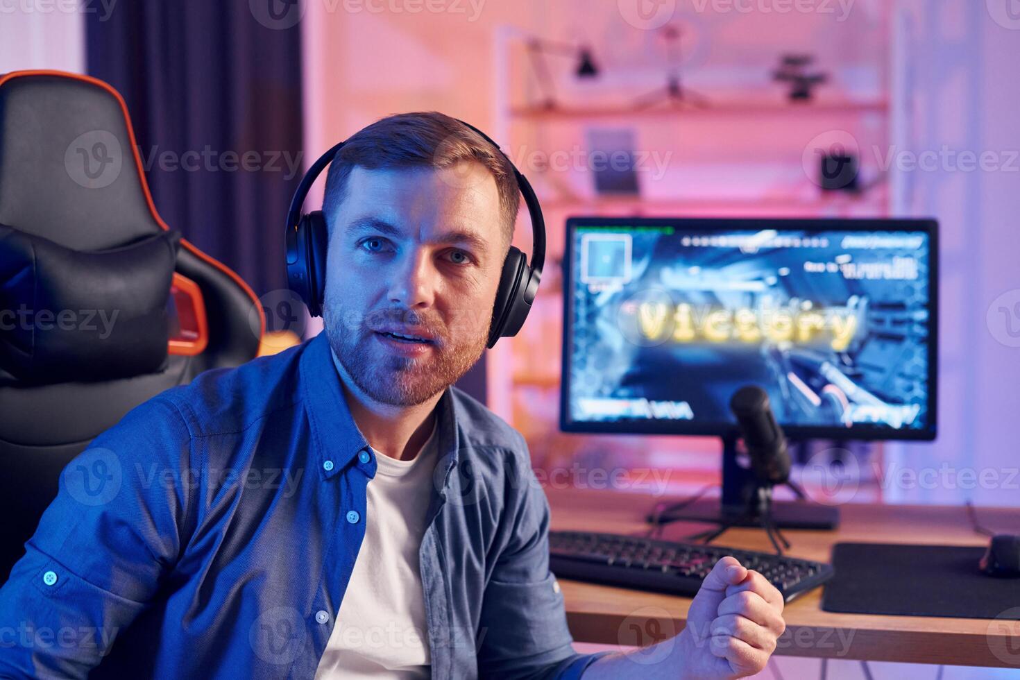A man is sitting in front of a computer with headphones on photo