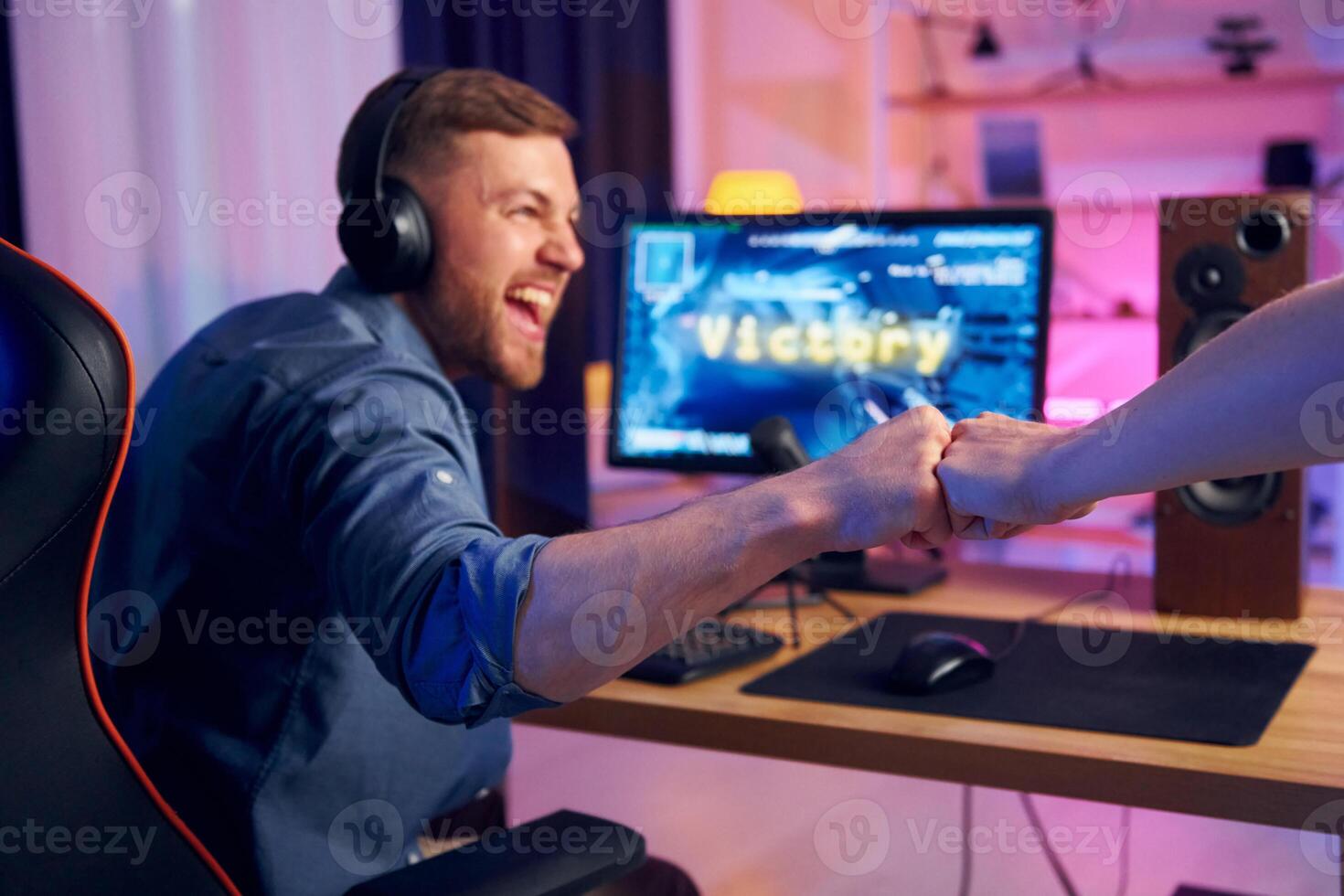A man is shaking hands with another person at a computer photo