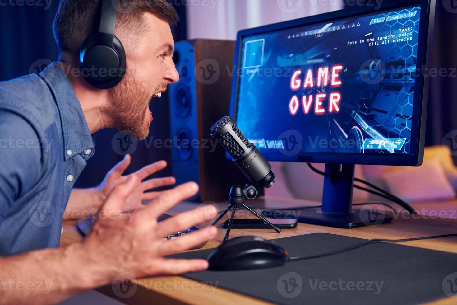 A man is screaming at a computer screen with the words game over photo