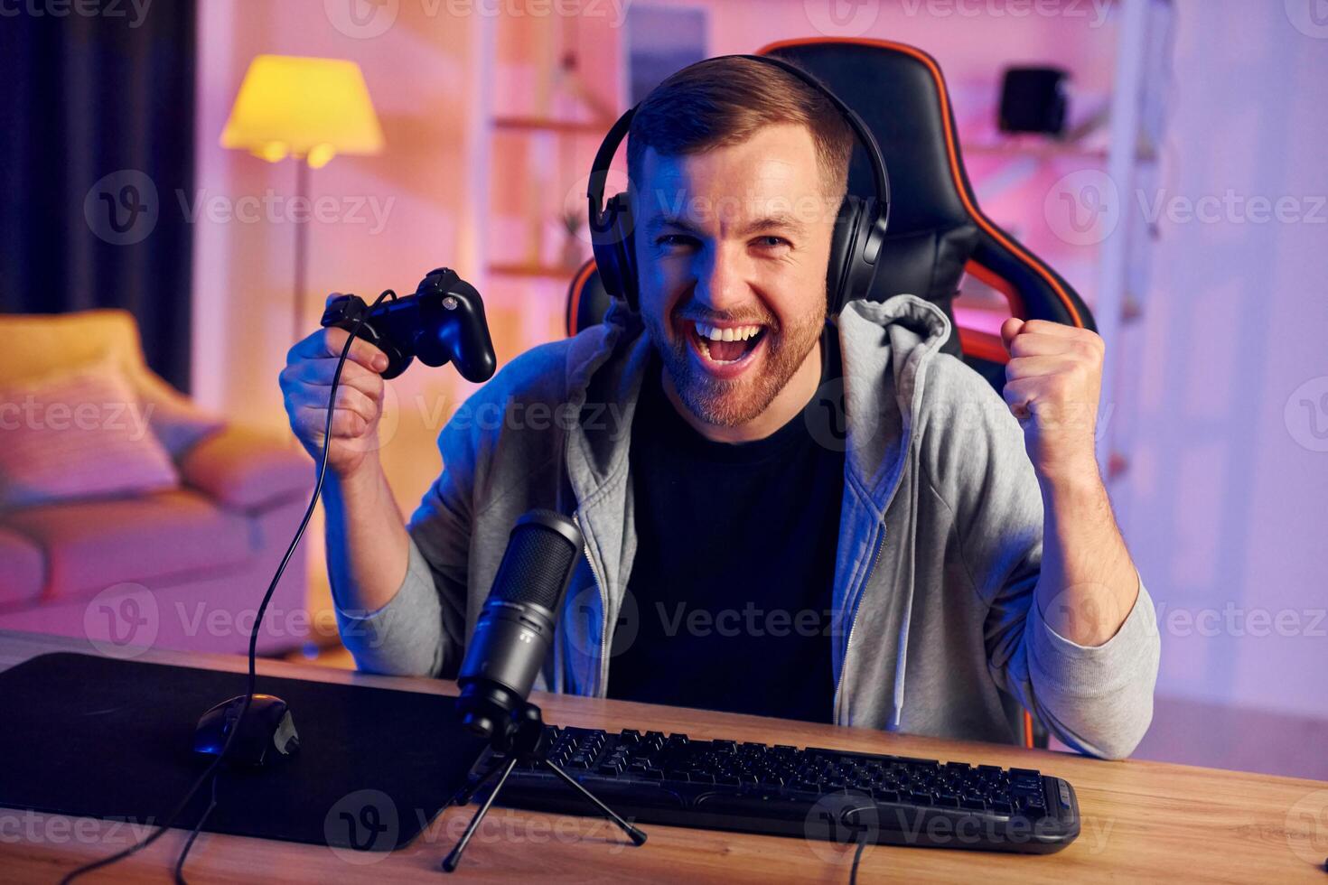 A man is sitting at a desk with a controller and headphones photo