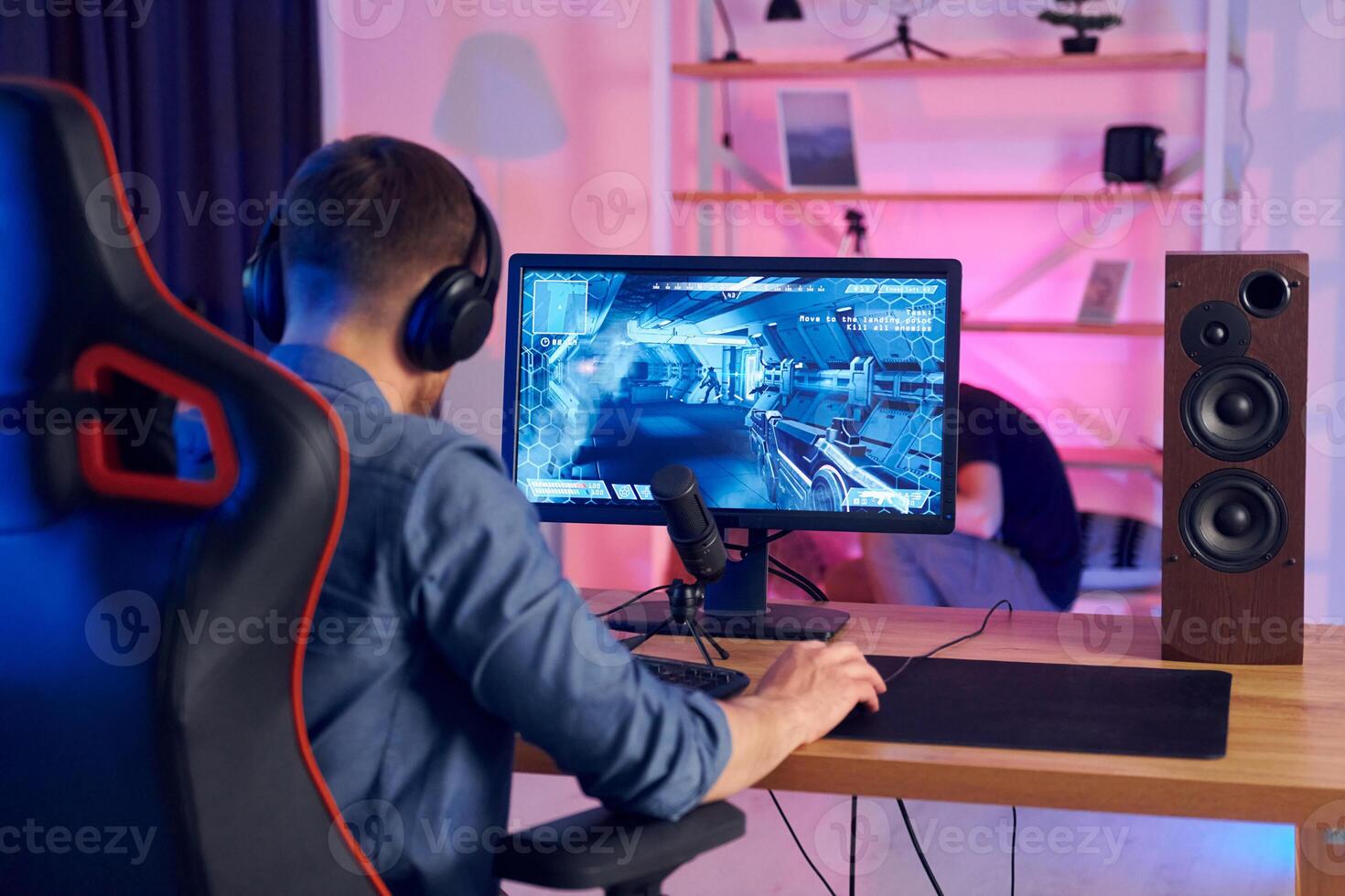 A man is sitting at a desk with a computer and a headset photo
