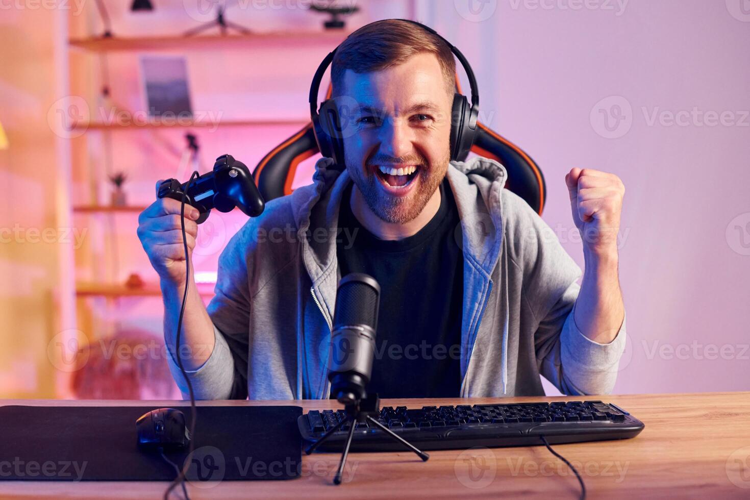 A man in a headset is sitting at a desk with headphones on photo