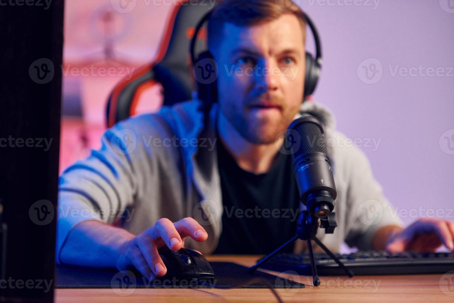A man in headphones is sitting at a desk with a microphone photo