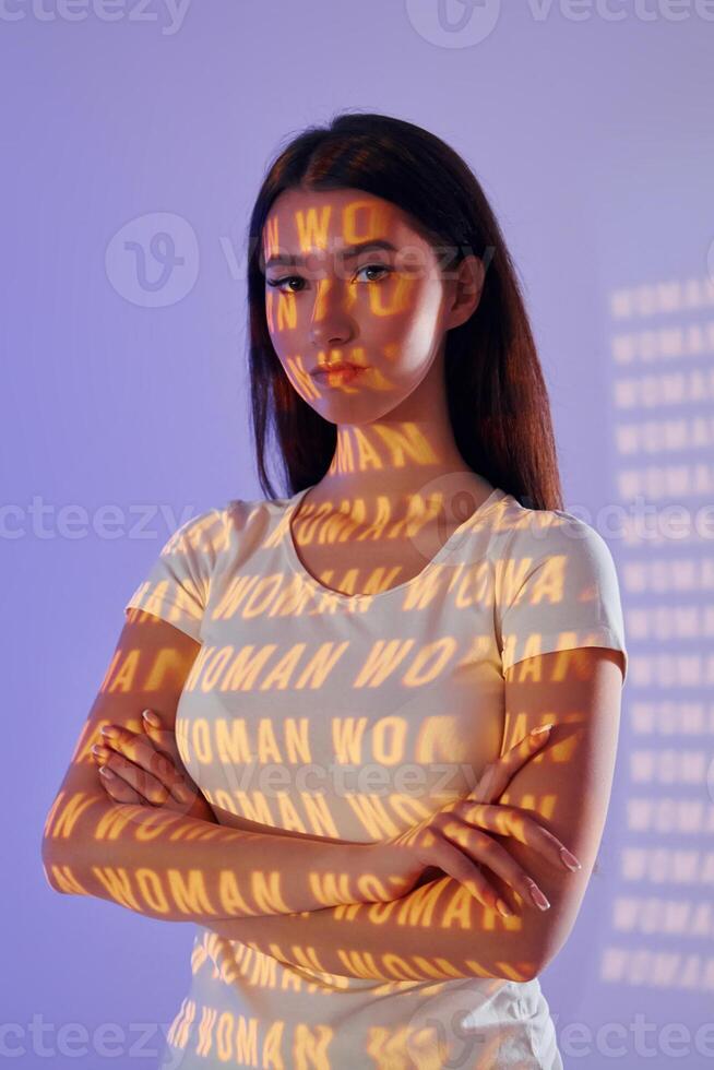 A woman with her arms crossed in front of a wall photo