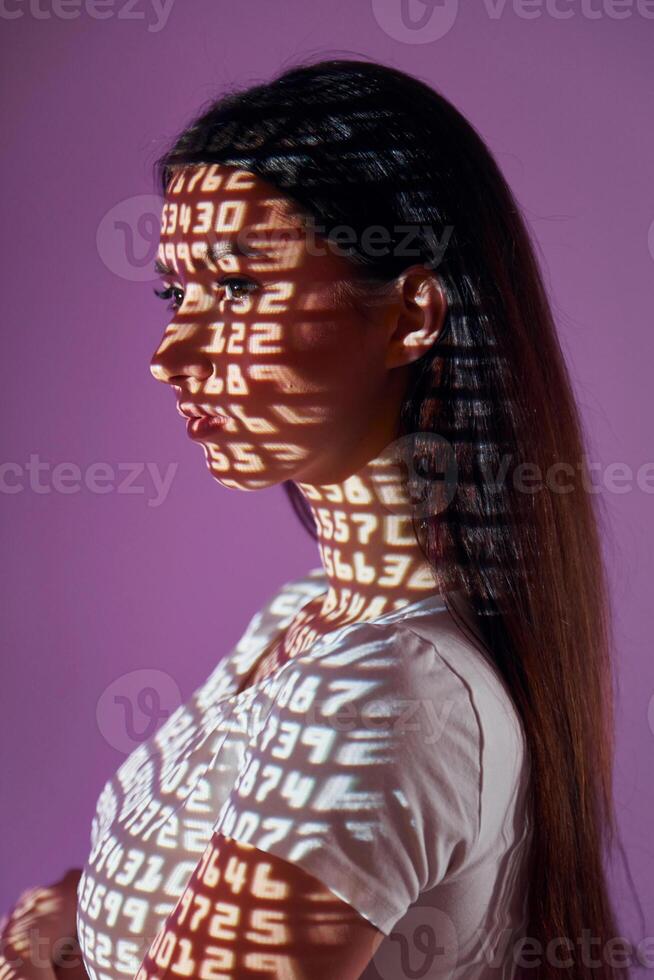 A woman with her arms crossed and her shadow projected on her face photo