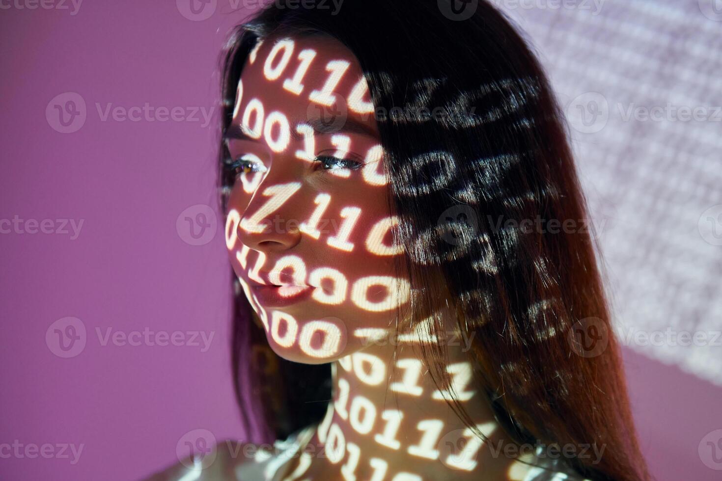 A woman with her face projected onto a wall with binary code photo