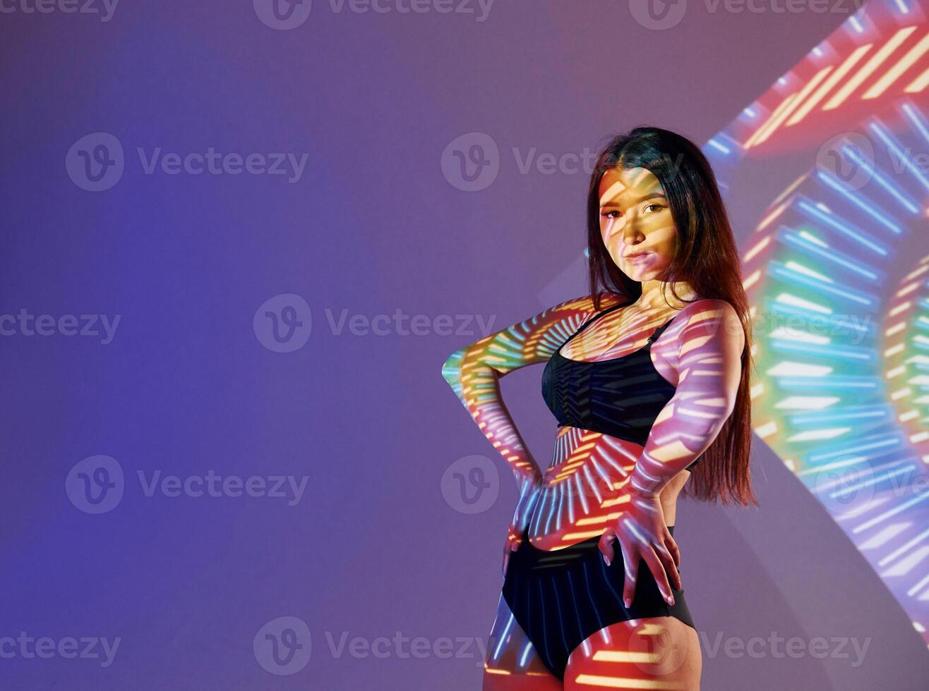 A woman in a bikini posing in front of a colorful light photo