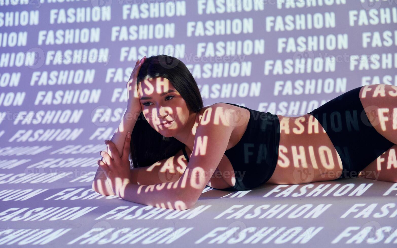 A woman laying on a bed with the words fashion on the wall photo