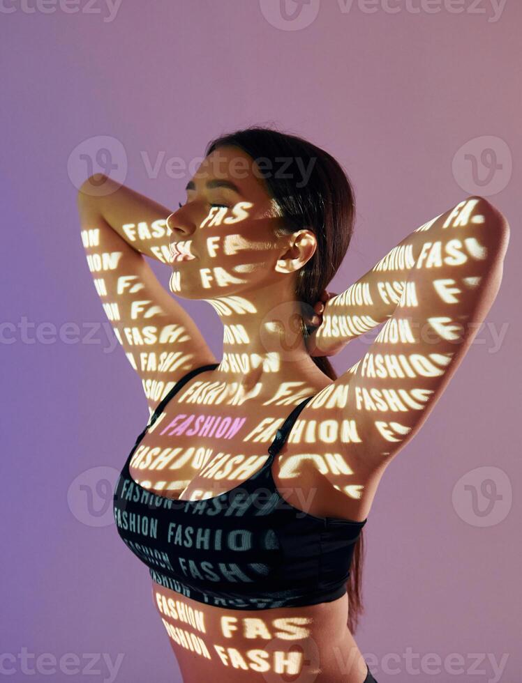 A woman in a bra top with words projected on her body photo