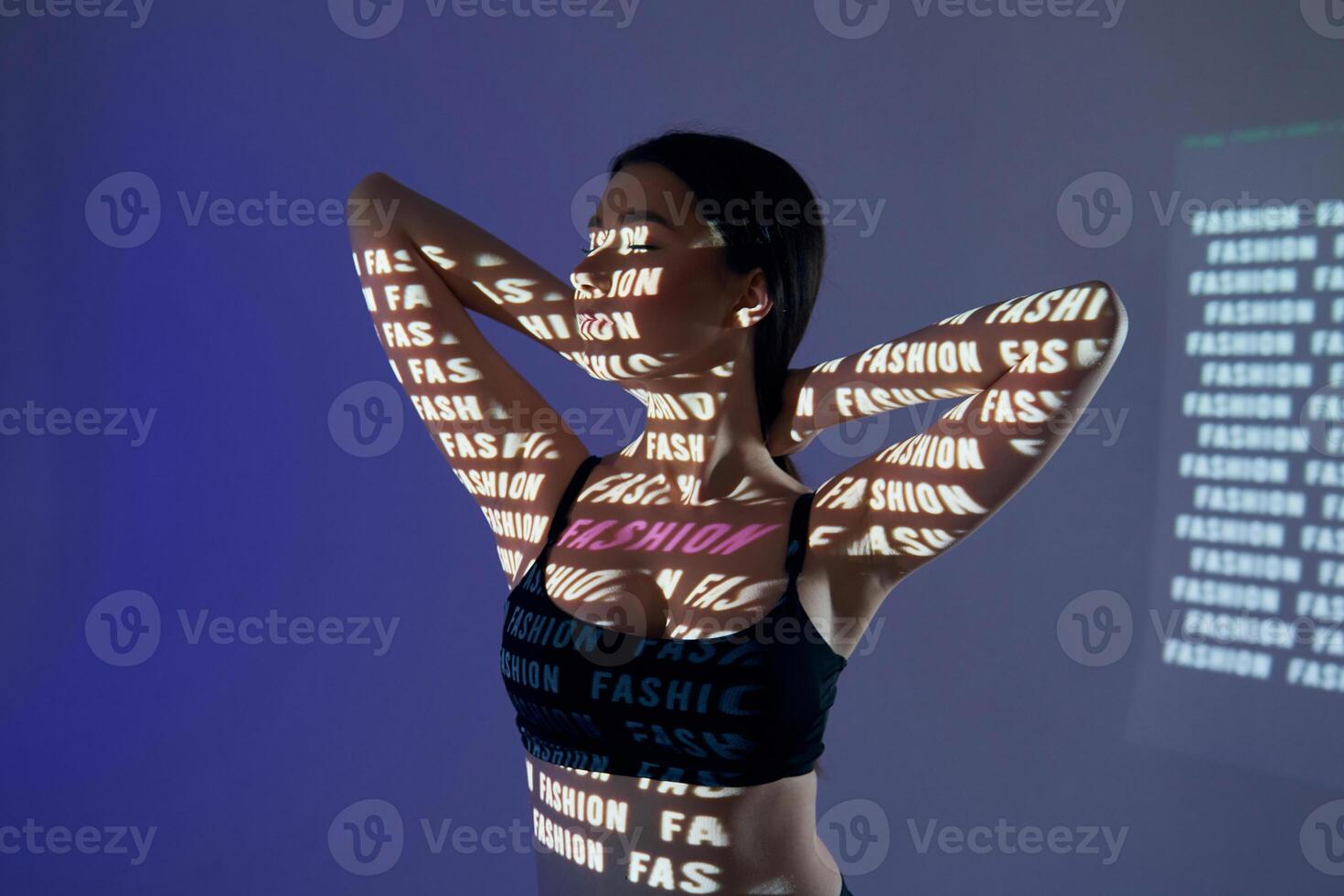 A woman in a sports bra is holding her arms up photo