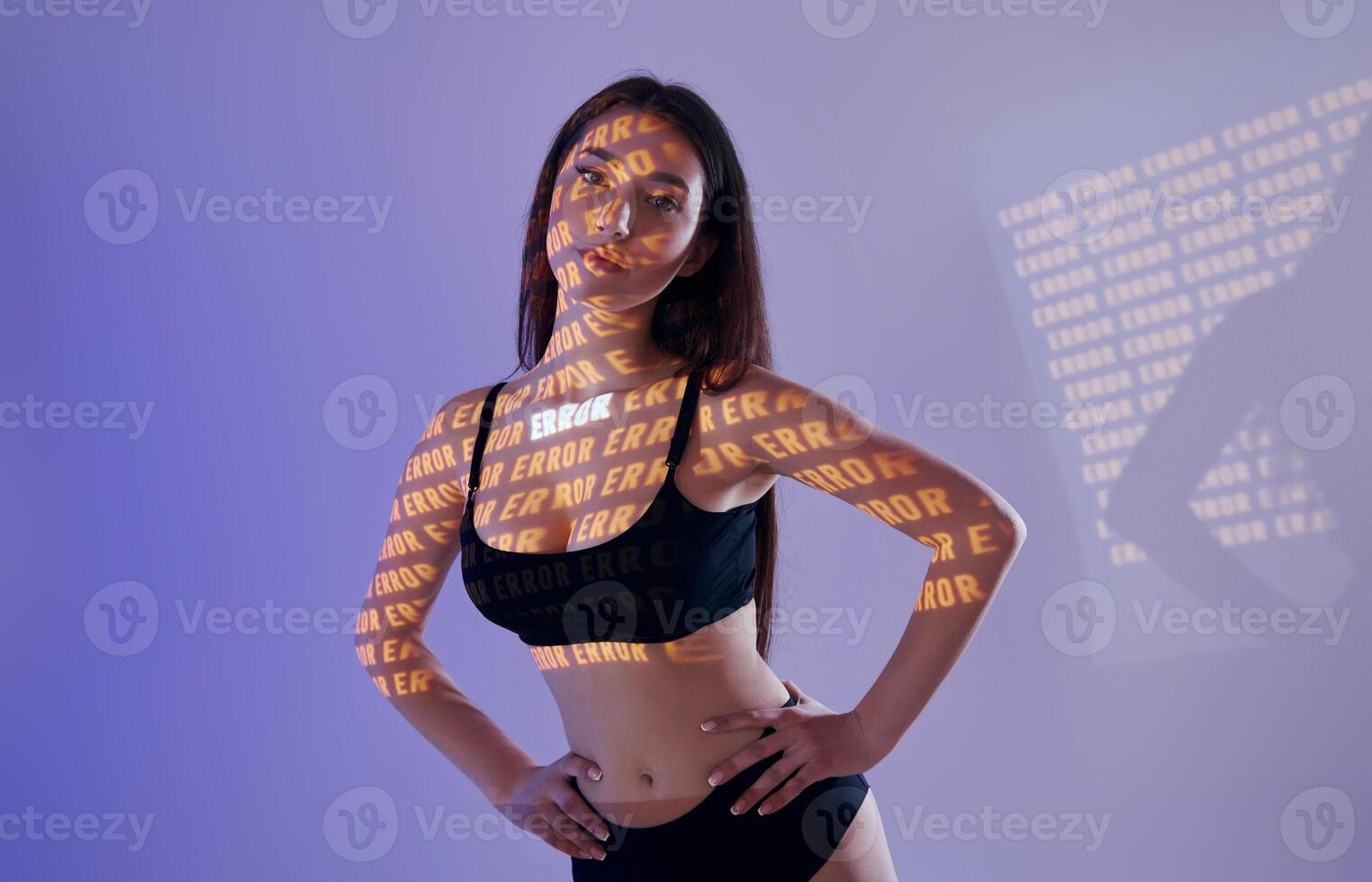 A woman in a black bra top and underwear standing in front of a wall with words on it photo