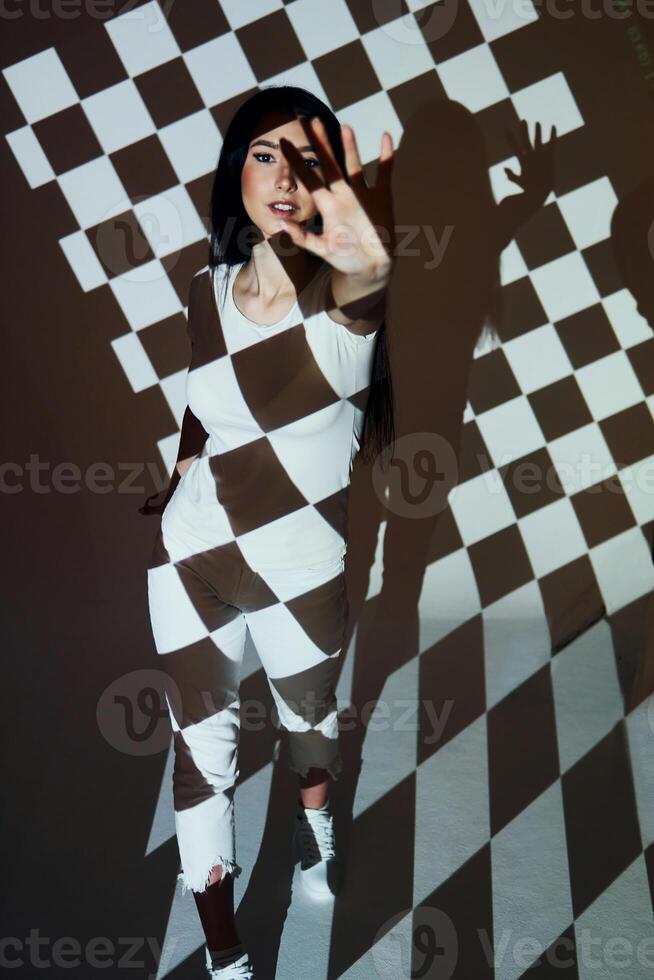 A woman in a checkered outfit standing in front of a checkered background photo