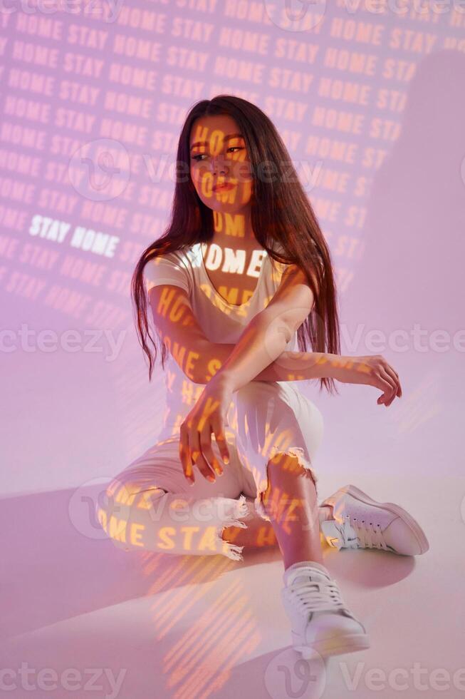 A woman sitting on the floor with neon text photo