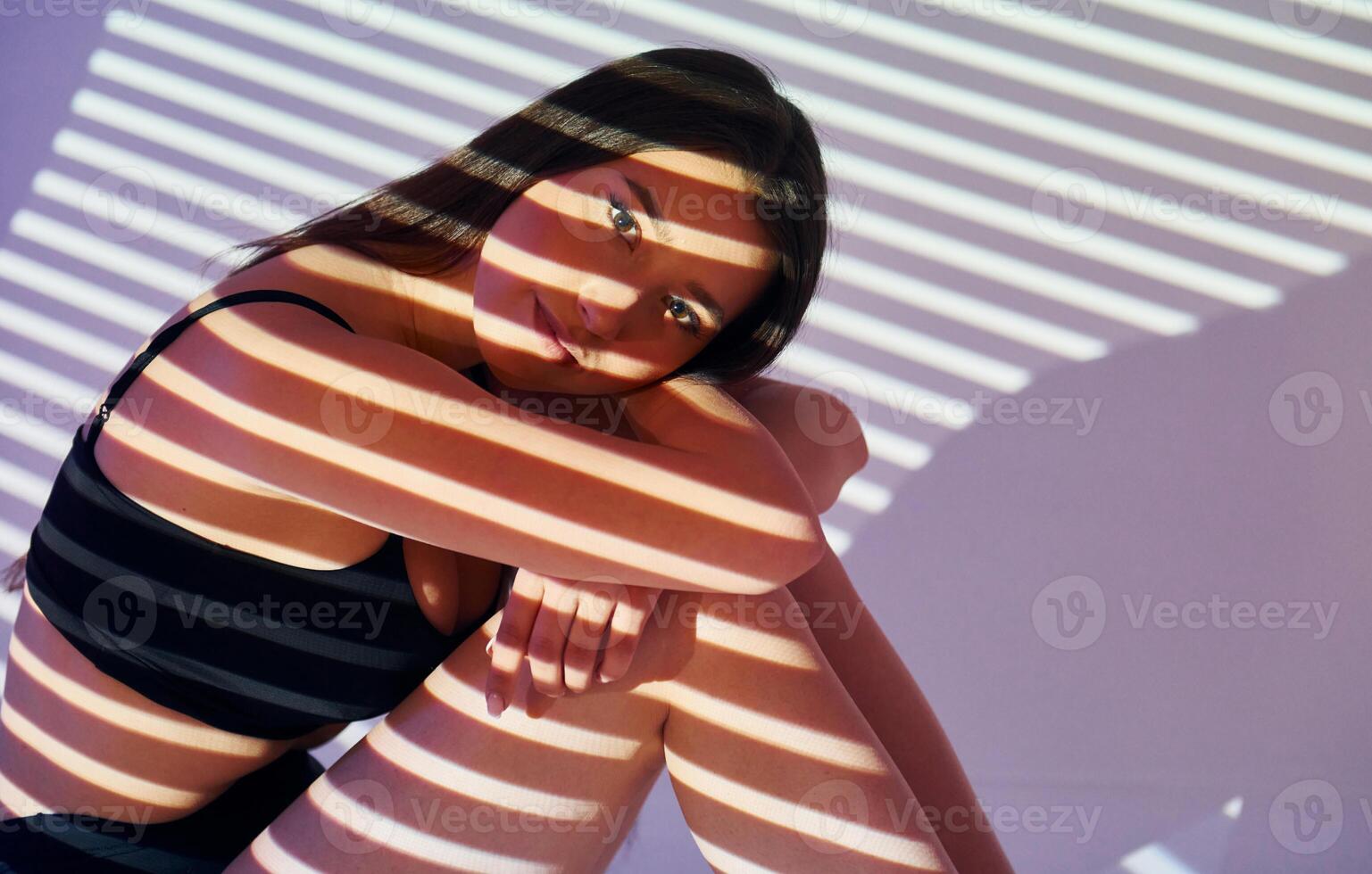 A woman in a bikini is sitting on a bed photo