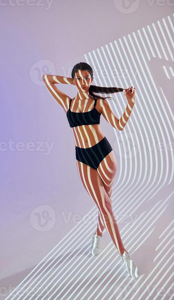 A woman in a bikini posing in front of a light photo