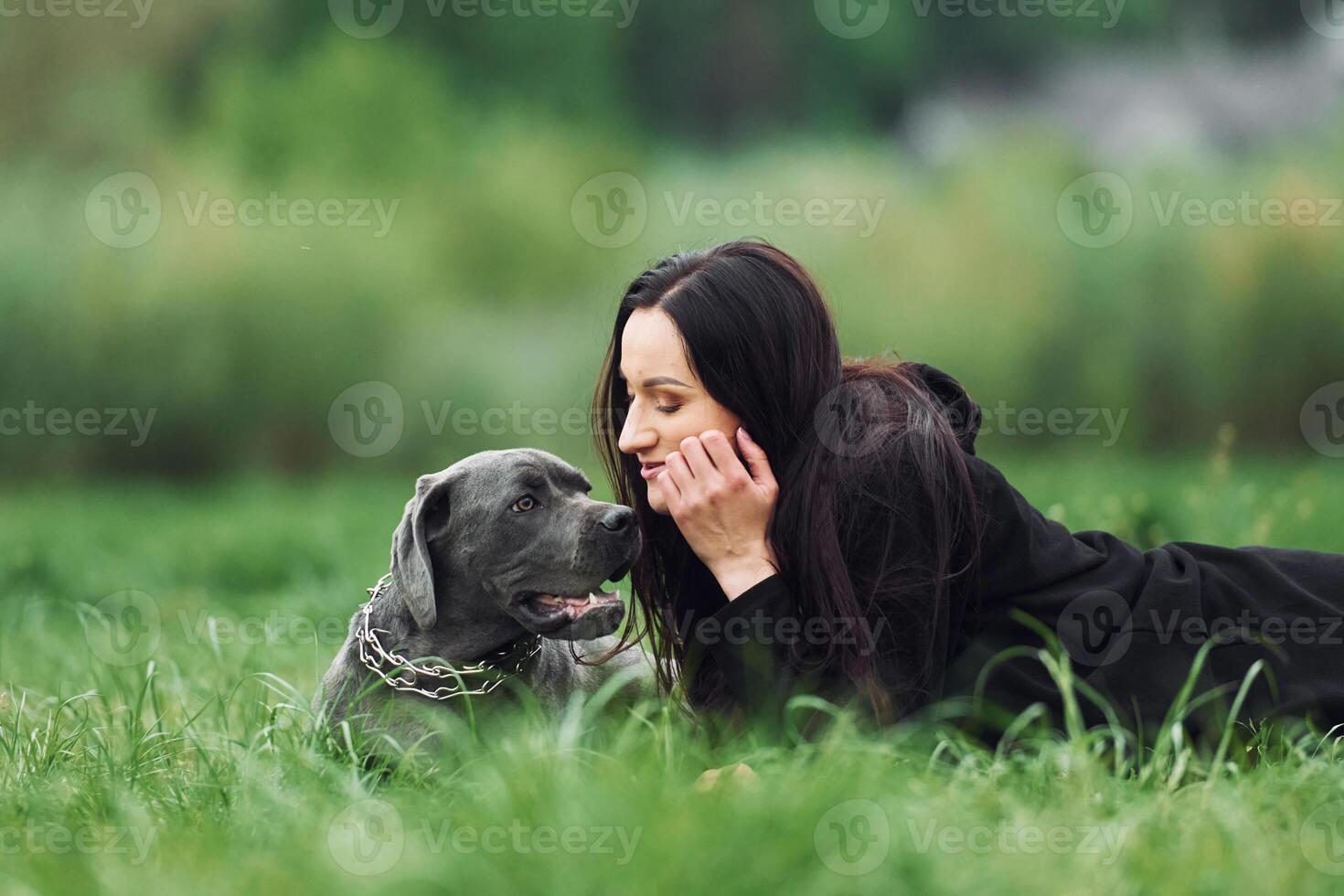 A woman laying in the grass with her dog photo
