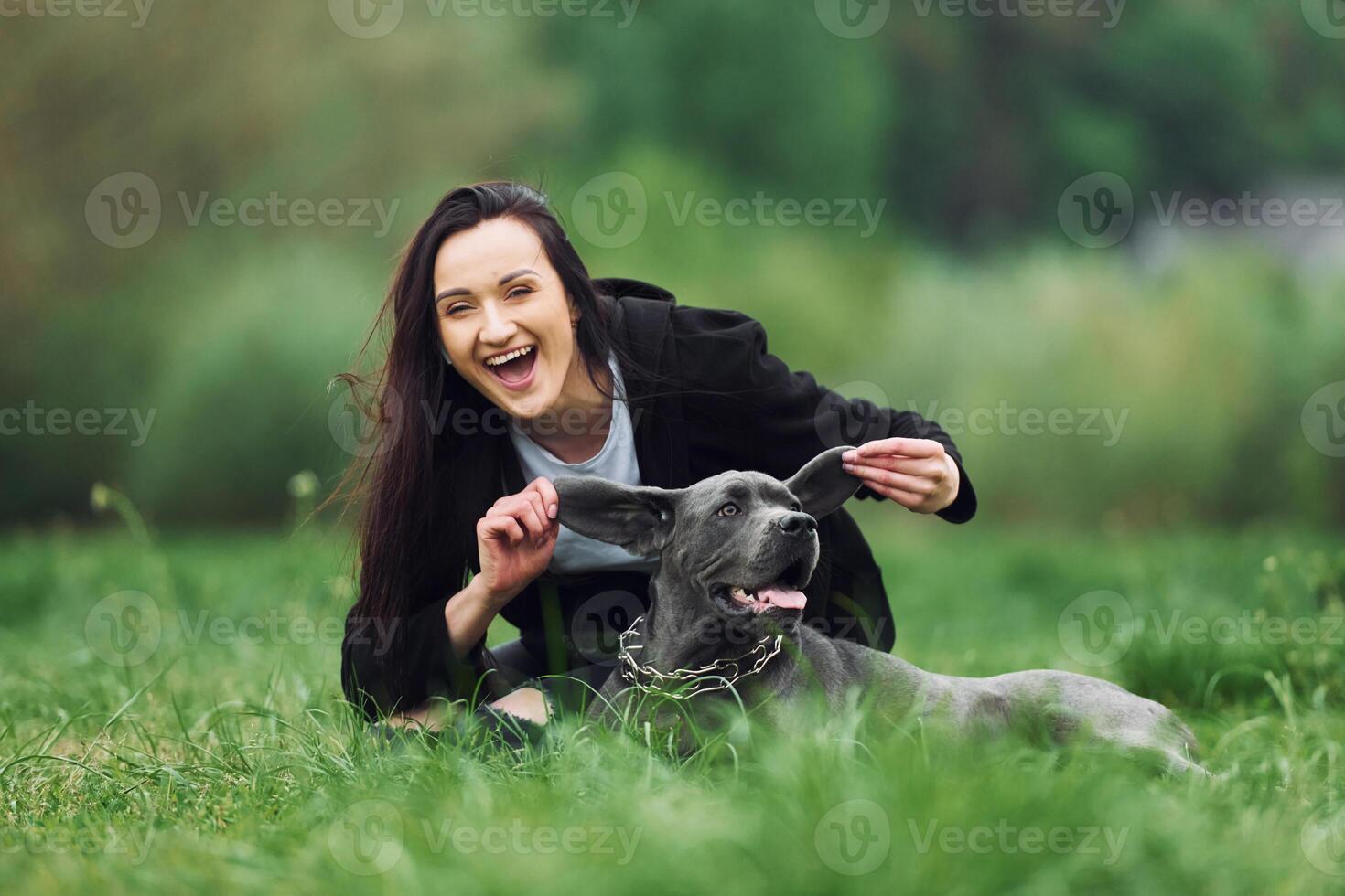 A woman is playing with her dog in the grass photo