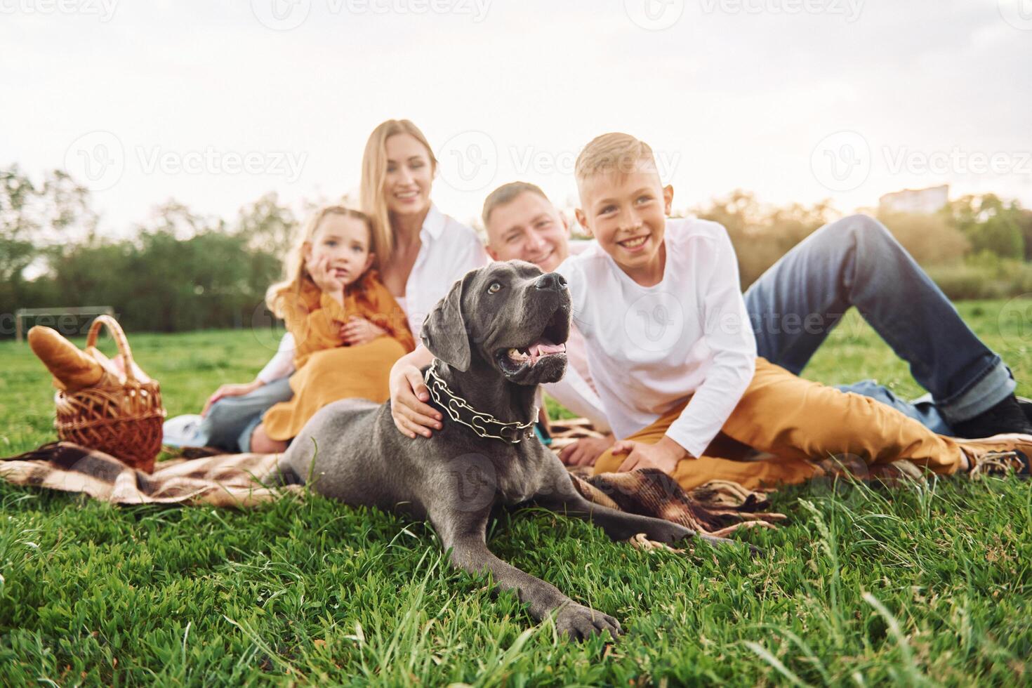 A family sitting on the grass with their dog photo