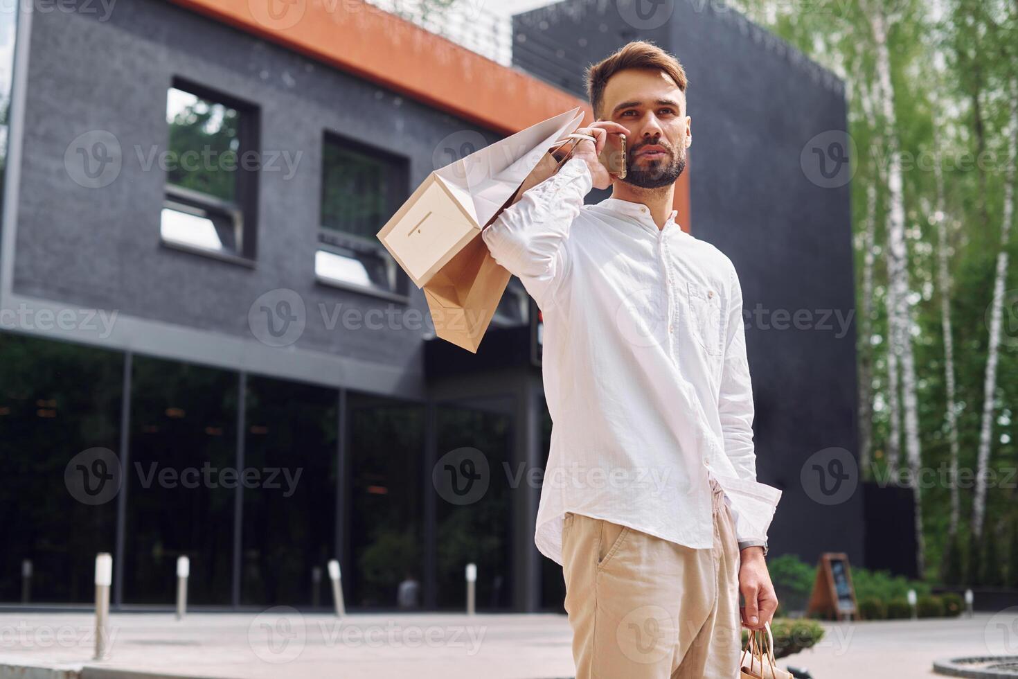 A man is holding a shopping bag and talking on the phone photo