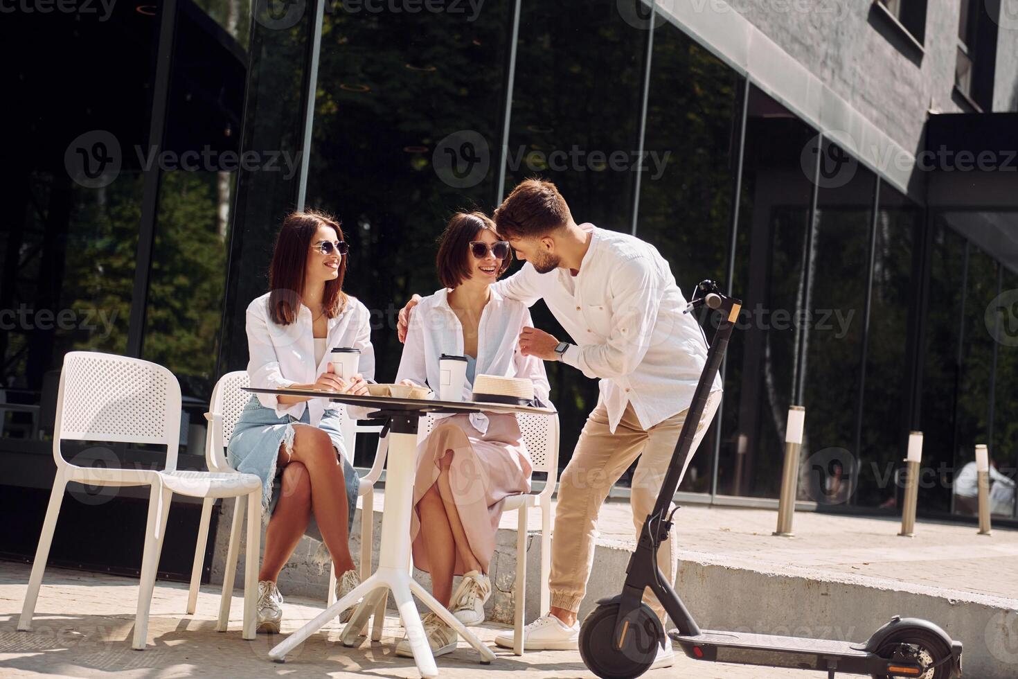 Three people sitting at a table with a scooter photo