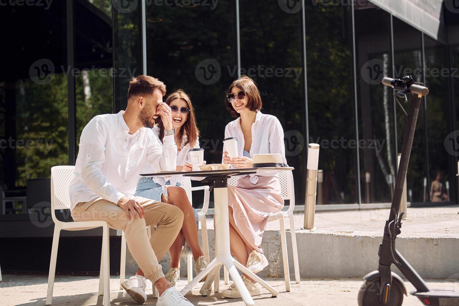 Three people sitting at a table with a scooter photo