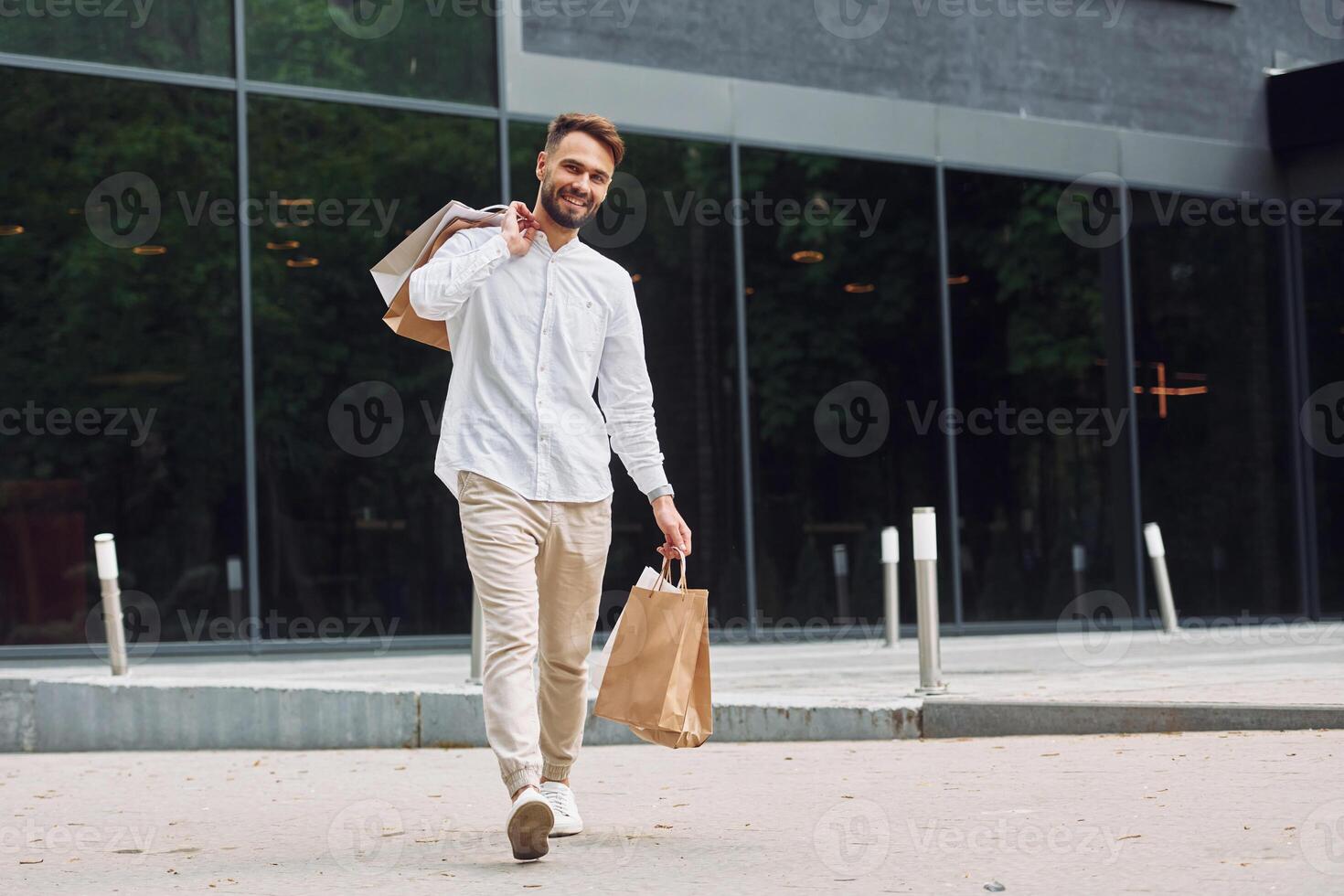 A man walking with shopping bags and talking on his phone photo