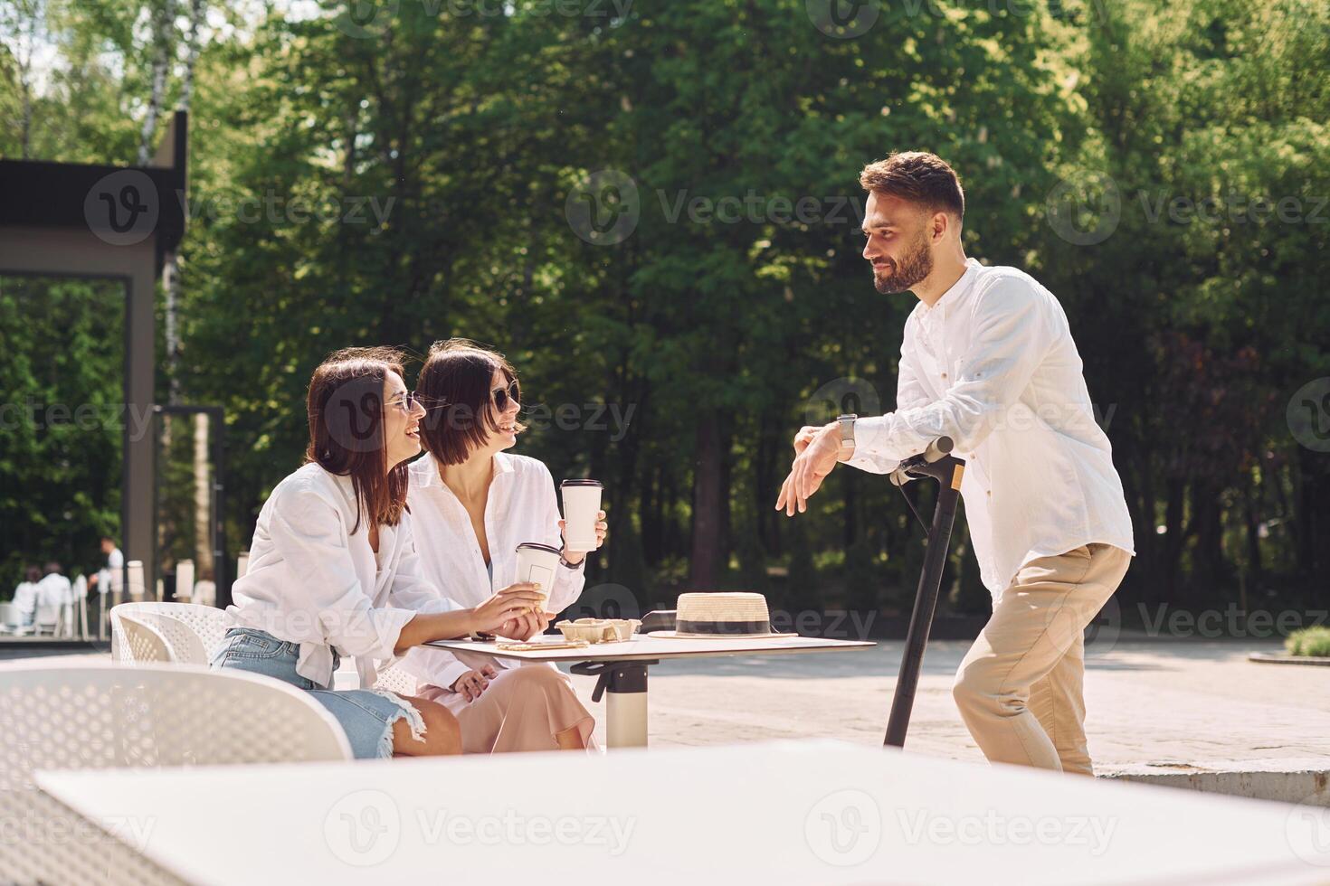 A man is standing in front of two women and a man is holding a camera photo