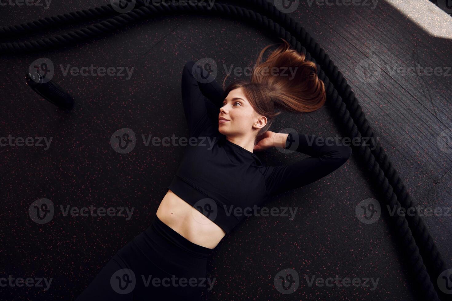 A woman in black top laying on the floor with a rope photo