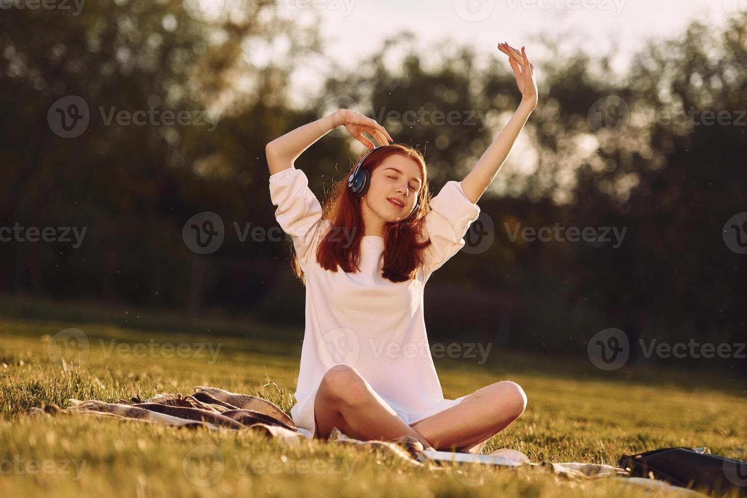 Moving to the music. Young girl is on the, field at sunny daytime having nice weekend photo